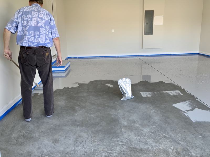 Installer spreading a gray base coat over ground concrete with a long-handled applicator