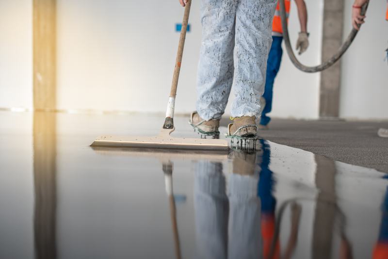Crew in spiked shoes leveling a fresh glossy floor coating with squeegees